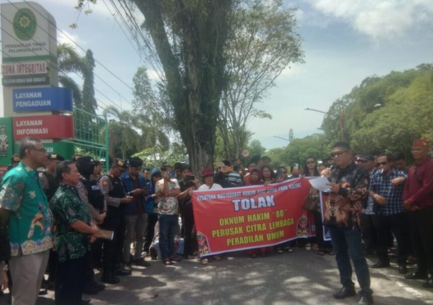 AKSI: Erko Mojra (tiga kiri,red) selaku koordinator Kesatuan Masyarakat Hukum Adat Kalimantan Tengah bersama puluhan masyarakat saat aksi di Pengadilan Tinggi Palangka Raya, Kamis (13/2/2025). (foto:ardi)