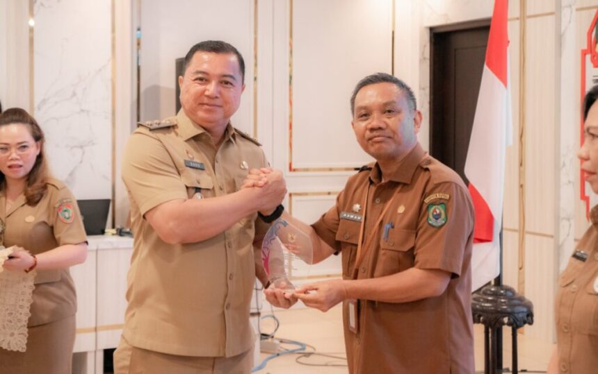Wakil Bupati Kapuas, Dodo menyerahkan penghargaan kepada Kepala Disarpustaka Kabupaten Kapuas, Asawan, atas keberhasilannya dalam penyelenggaraan kearsipan pengawasan eskternal kabupaten dan kota (Foto : Ist)